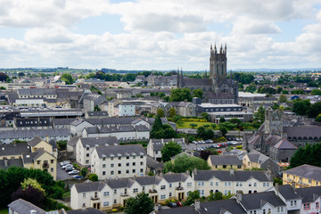 View over Kilkenny city, Ireland, from the round tower of St Canice's Cathedral with a mix of modern and medieval architecture under a cloudy sky and St Mary's Cathedral rising over the town. - obrazy, fototapety, plakaty