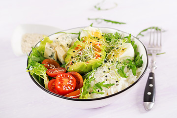 Healthy green vegetarian buddha bowl lunch with eggs, rice, tomato, avocado and blue cheese on table. Trend cuisine.