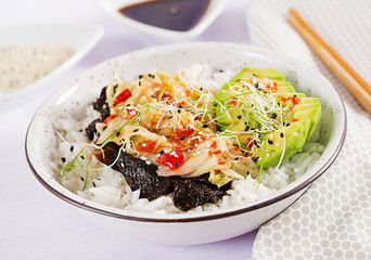Vegan salad  with rice, pickled kimchi cabbage, avocado,  nori and sesame on bowl. Sushi-food hybrids trend. Overhead