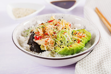 Vegan salad  with rice, pickled kimchi cabbage, avocado,  nori and sesame on bowl. Sushi-food hybrids trend. Overhead