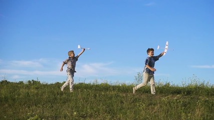 two boys running with his airplanes at field