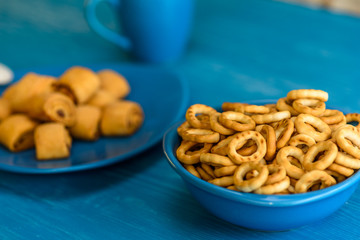 Small and very dry bagels in a blue bowl photographed on a vintage wooden background.