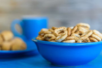 Small and very dry bagels in a blue bowl photographed on a vintage wooden background.