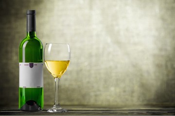 Red wine glass on wooden desk at wall background