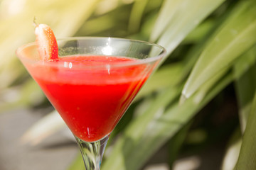 A glass of strawberry cocktail on a grass background