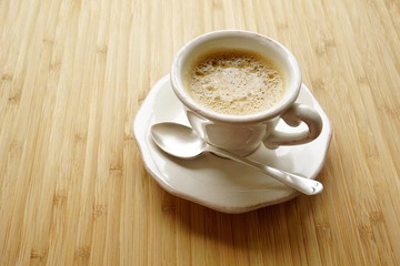 Coffee espresso in a fancy cup, wooden table, silver teaspoon