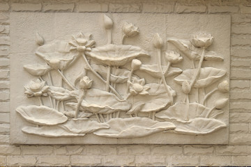 Beautiful white lotus stucco patterned on the boundary wall. Vintage white wall bas-relief stucco in plaster, depicts Lotus flowers background.