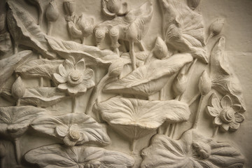 Beautiful white lotus stucco patterned on the boundary wall. Vintage white wall bas-relief stucco in plaster, depicts Lotus flowers background.