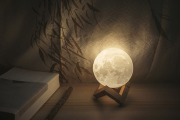 Moon lamp on desk, light at night, reading book on wooden table, with Chinese blinds and wooden...