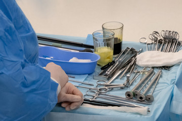 Hands of a nurse or medical assistant on a table with surgical instruments. Glasses with...