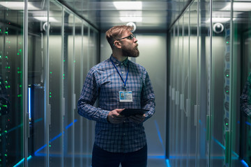 Adult bearded engineer in server room - Powered by Adobe