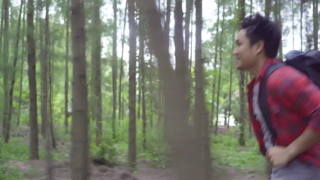 Hiker Asian backpacker man on hiking adventure feeling freedom walking in forest, Male enjoy his holidays near lots of tree. Lifestyle men travel and relax in freetime concept.