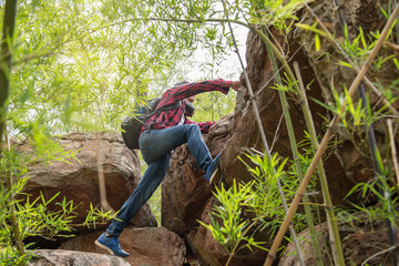 Asian man climbing rock mountain on sunset