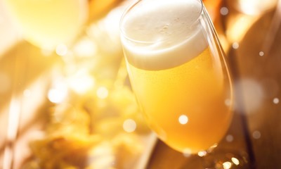 Glass of light beer on background