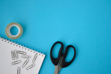 spiral notebook and scissors on blue background