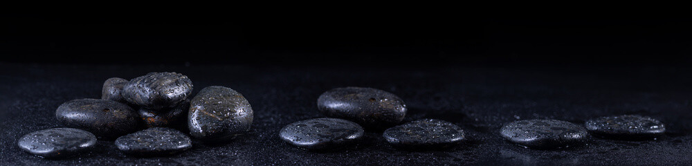 Panoramic image of zen stones with water drops on a black background