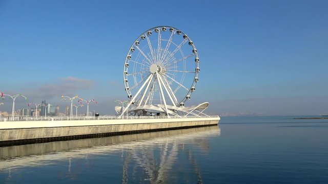 View of the Ferris wheel on the Caspian sea. Sunny January day (timelapse). Baku, Azerbaijan