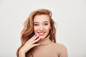 Enjoying her beauty. Beautiful girl with charming smile posing in studio, looking at camera isolated over grey background