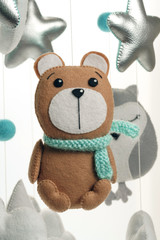 A felt toy in the form of a bear, part of a children's mobile. On a white background.