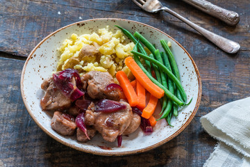 Pork in cranberry glaze with red onions, crushed potatoes and boiled vegetables - high angle view