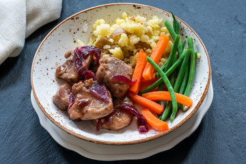 Pork in cranberry glaze with red onions, crushed potatoes and boiled vegetables - high angle view