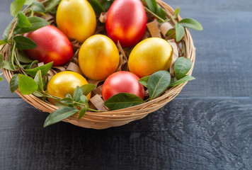 Easter eggs in a wicker basket on a dark wooden background.