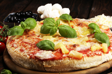 Delicious pizza with pineapple, ham slice, bacon slice, mozzarella cheese, pizza sauce on rustic background for fast food and ready to eat concept