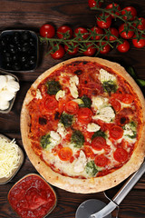 Pizza with tomatoes, mozzarella cheese, black olives and basil. Delicious italian pizza on wooden pizza board.