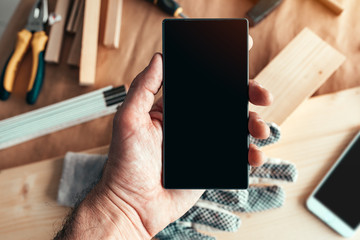 Handyman maintenance worker holding smartphone with blank mock up screen