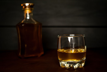 bottle of whiskey and a glass of whiskey on a wooden background