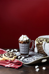Hot chocolate with marshmallows and cookies on a red background