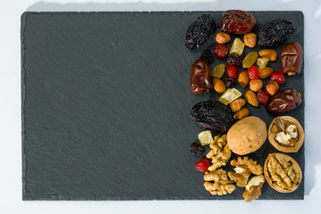 Still life from nuts and dried fruits on a slate plate.