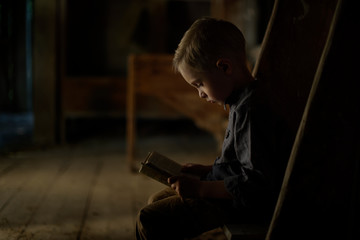 Fototapeta na wymiar A boy in an old house reading a mysterious book. Fun in search of treasure.