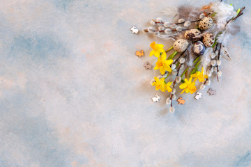 Easter decoration – pussy willow, narcissus, bunny figurines and natural eggs. Top view, close up, flat lay on light concrete background