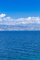 Wonderful romantic summertime  seascape. Sailing yacht with white sails in to the crystal clear azure sea against coastline slopes.