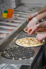 Baker lays chicken meat on the pizza base spread by mayonnaise