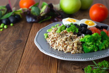 Quinoa salad with green pea,broccoli, olives. Healthy food, lunch over wooden background. Vegetarian food, snack.