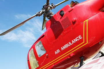 Red helicopter of air ambulance isolated on blue sky background. Detail of the helicopter blades....