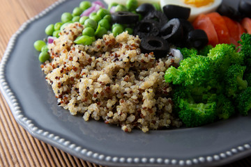 Healthy detox dish with egg,green peas, quinoa, fresh tomato and broccoli on wooden background, top view
