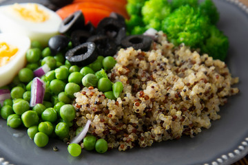 Healthy detox dish with egg,green peas, quinoa, fresh tomato and broccoli on wooden background, top view