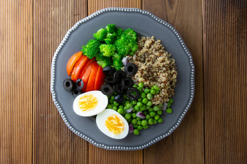 Colorful quinoa buddha plate withbroccoli, egg, spring onion, tomatoes and green peas. Home made food. Concept for a tasty and healthy vegetarian meal. Top view. Copy space.