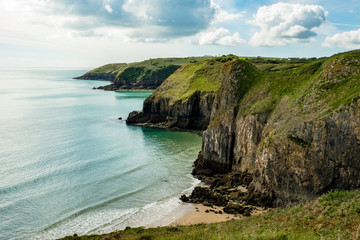 Fototapeta na wymiar Sandstrand umrahmt von steilen Klippen entlang des Pembrokeshire Coast Paths in Wales, Großbritannien