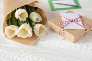 White tulips bouquet and gift box, copy space on white wooden background, spring holidays gift concept.