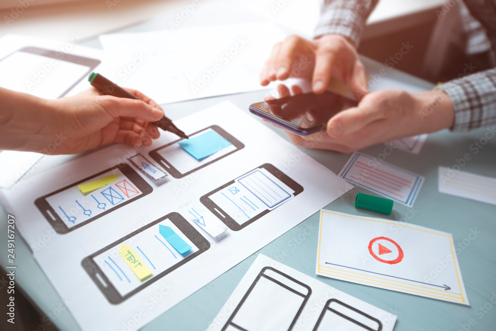 Poster close-up of the hands of a web designer developing applications for mobile phones. two app design wo