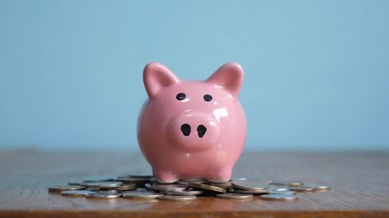 piggy bank business standing on a pile of coins concept. A hand is putting coin in a piggy bank on a yellow background. saving money is an investment for the future. Banking investment and finance - Powered by Adobe