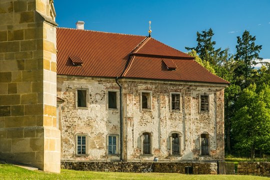 Kladruby, Czech Republic / Europe - July 7 2018: Monastery of Benedictine from 12th century, a building made of bricks, new red roof, old windows, golden star on top, green grass and trees, sunny day
