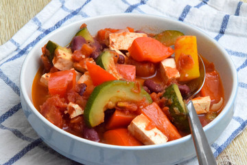 Vegan meal served with beans, tofu, zucchini, pepper, tomatoes and onions