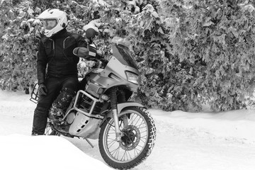 Naklejka premium Rider man on adventure motorcycle. Winter fun. snowy day. the snow under the wheels of a motorbike. Enduro. off road dual sport travel tour, black and white. winter clothes, equipment