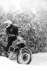 Naklejka premium Rider man in action on adventure motorcycle. Winter fun. snowy day. ride on snow road. travel tour, active life style concept. winter clothes, equipment, copy spase, vertical photo, black and white