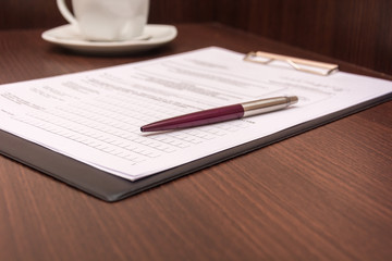 White notepad on a wooden table. Record thoughts under a cup of coffee.